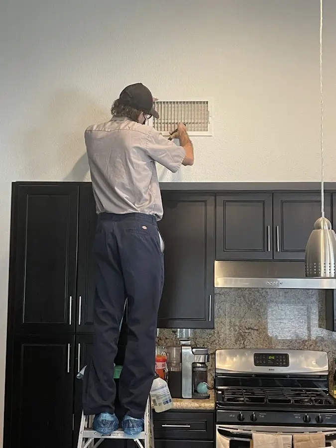 Technician inspecting an air vent during HVAC service in Sikeston